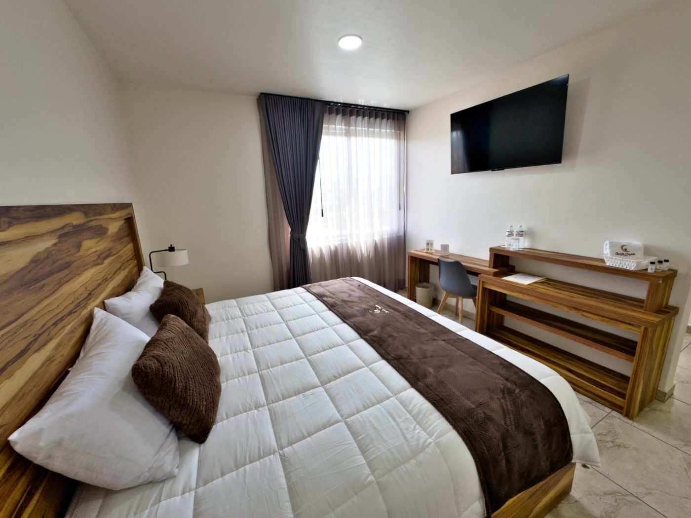 Habitación King de Quinta Candela Hotel con cabecera de madera y TV de pantalla plana